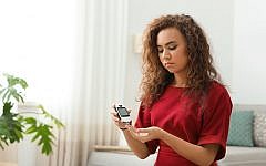 Young African-American woman using digital glucometer at home. Diabetes control